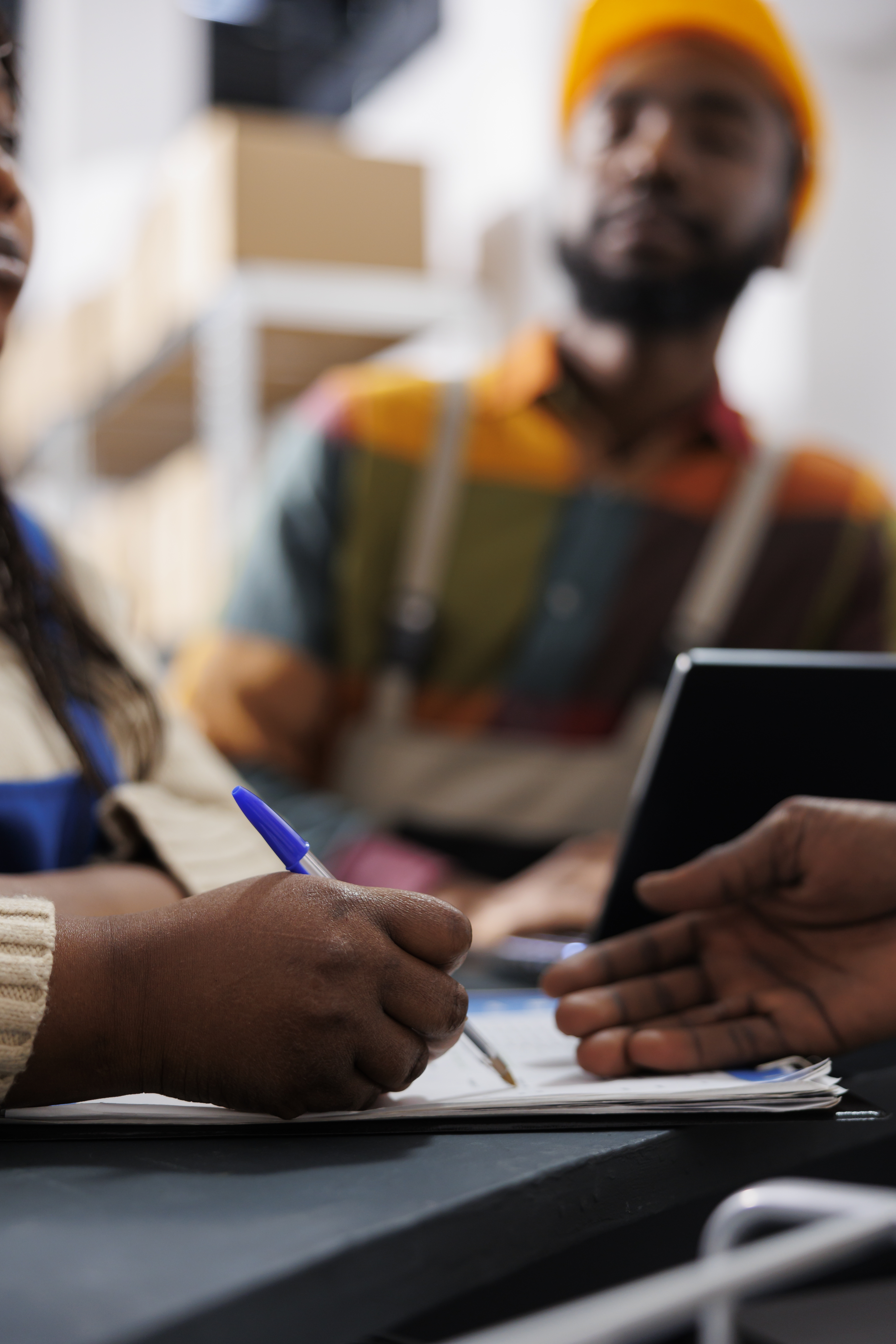 African american woman warehouse worker hand writing in clipboard at reception desk. Storehouse employees checking order list and managing documentation at post office checkout close up